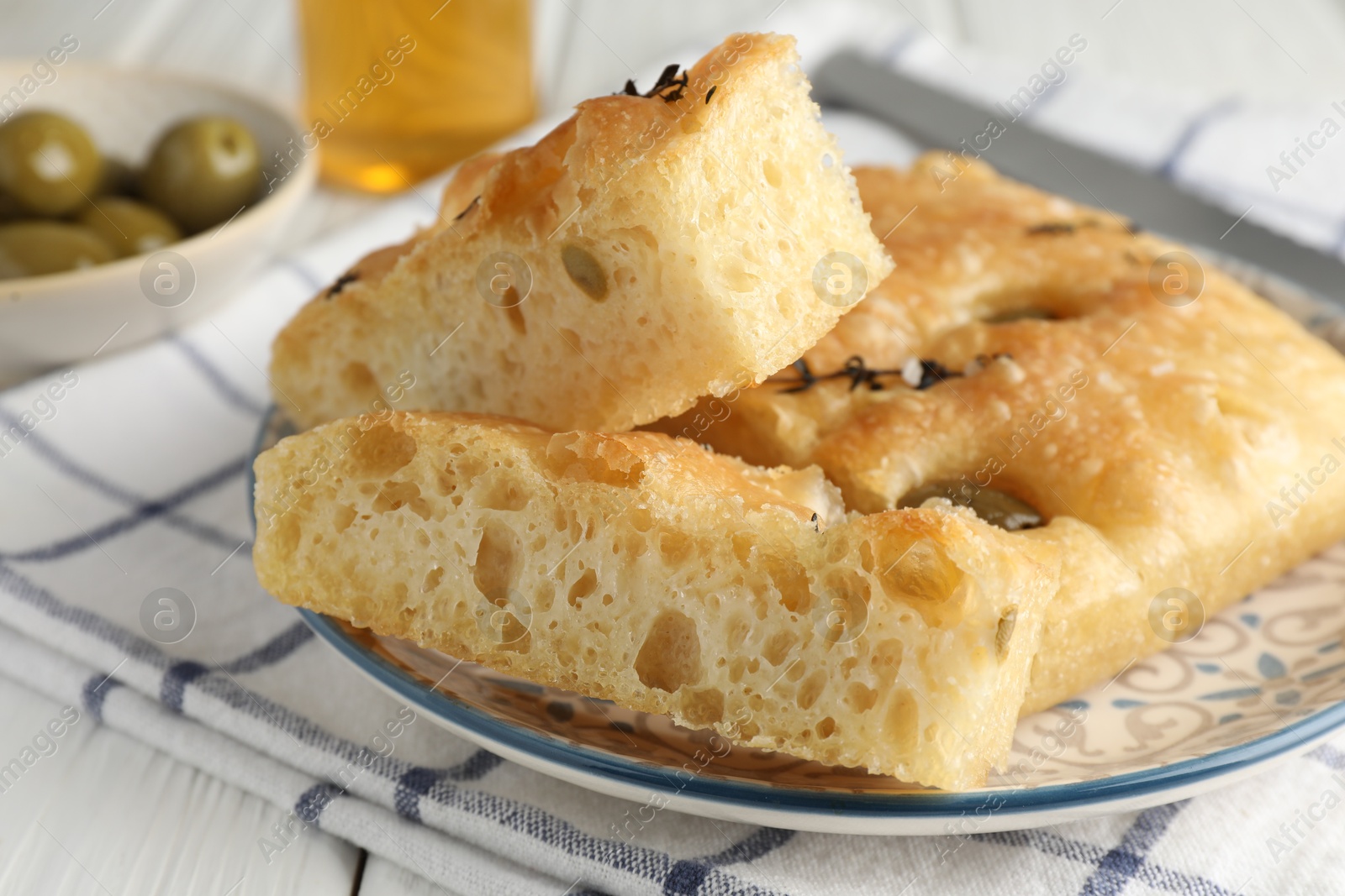 Photo of Slices of delicious focaccia bread with olives, thyme and salt on table, closeup