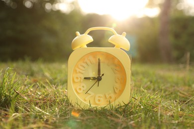 Photo of Yellow alarm clock on green grass outdoors