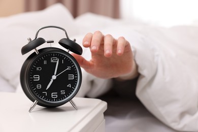 Photo of Man turning off alarm clock in bedroom, focus on hand