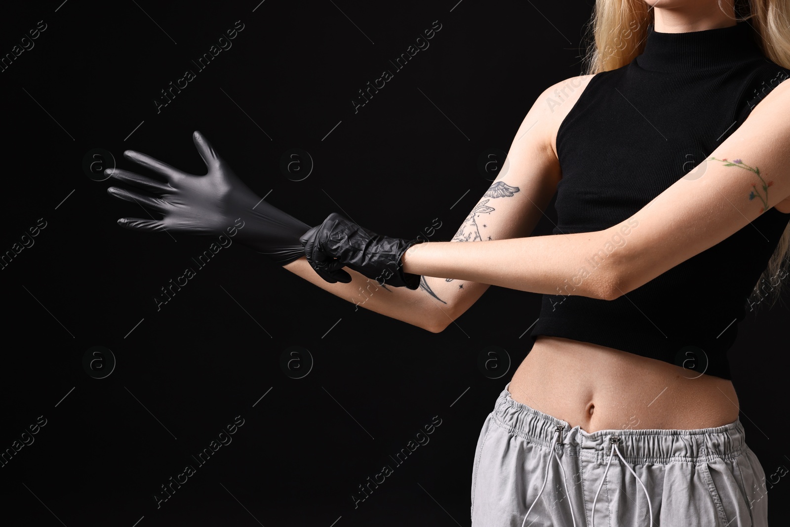 Photo of Professional tattoo artist wearing gloves on black background, closeup