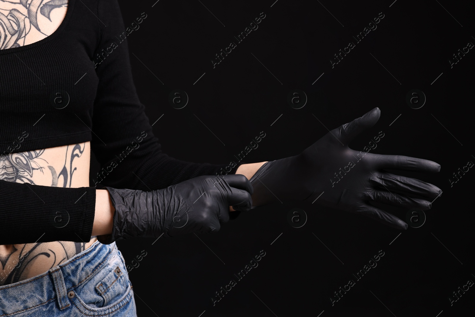 Photo of Professional tattoo artist wearing gloves on black background, closeup