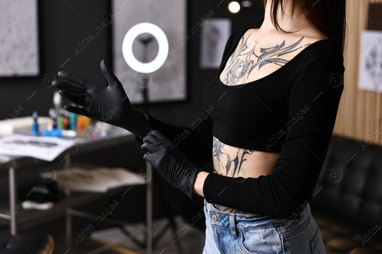 Photo of Professional tattoo artist wearing gloves in salon, closeup