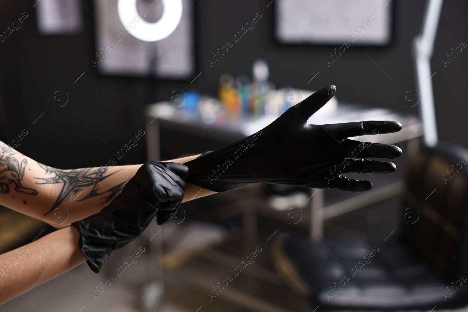 Photo of Professional tattoo artist wearing gloves in salon, closeup