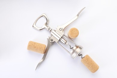 Photo of Wing corkscrew and corks on white background, top view