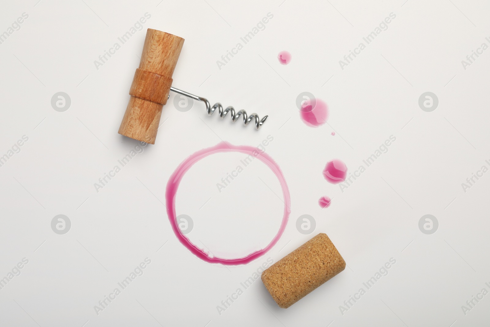 Photo of Corkscrew, cork and red wine stains on white background, top view