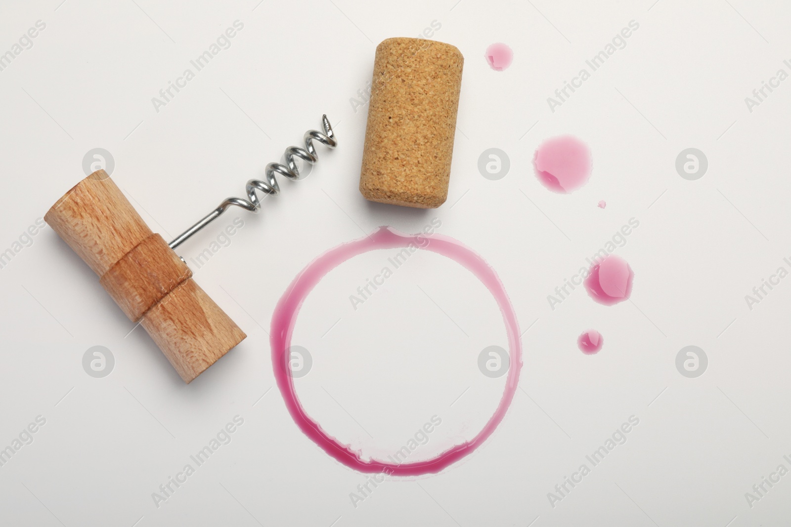 Photo of Corkscrew, cork and red wine stains on white background, top view