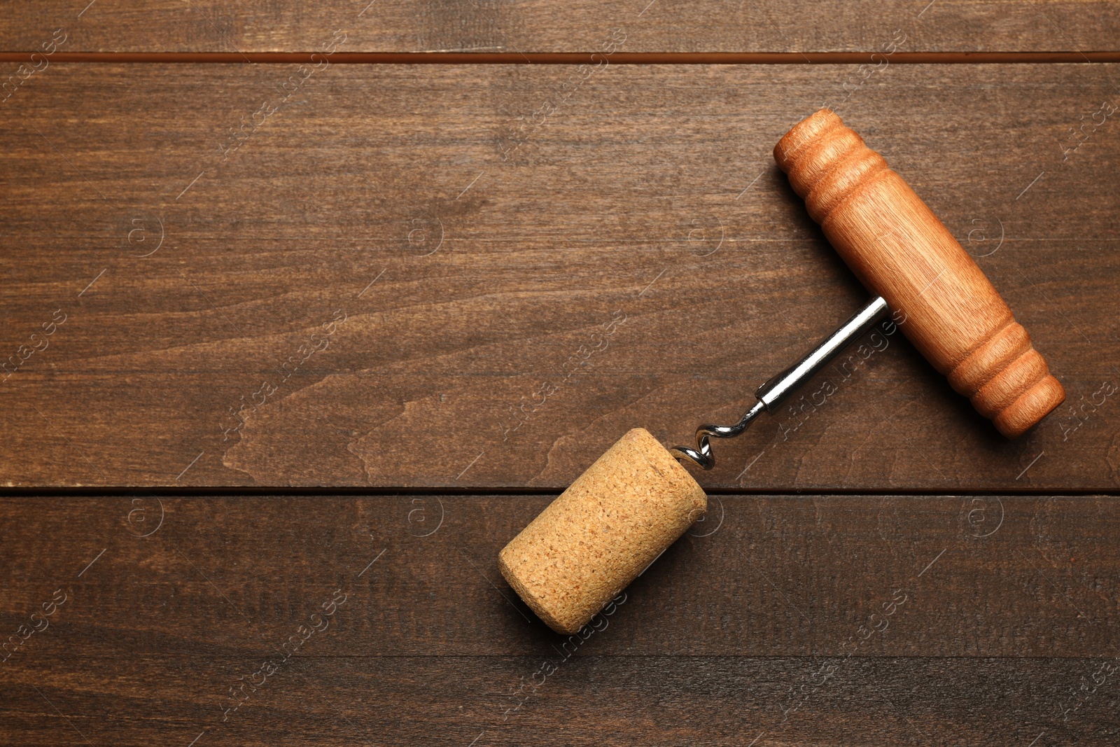 Photo of Corkscrew and cork on wooden table, top view. Space for text