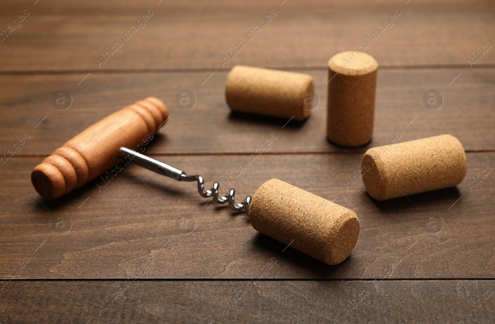 Photo of Corkscrew with handle and corks on wooden table