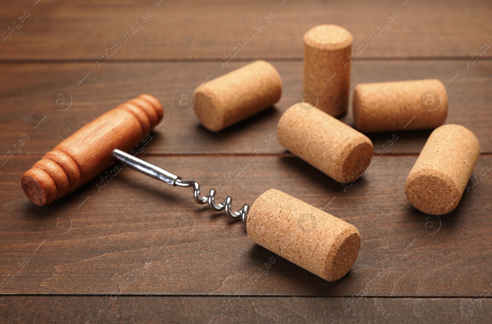 Photo of Corkscrew with handle and corks on wooden table