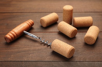 Photo of Corkscrew with handle and corks on wooden table