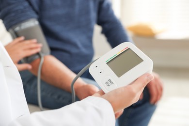 Photo of Doctor measuring patient's blood pressure in hospital, closeup