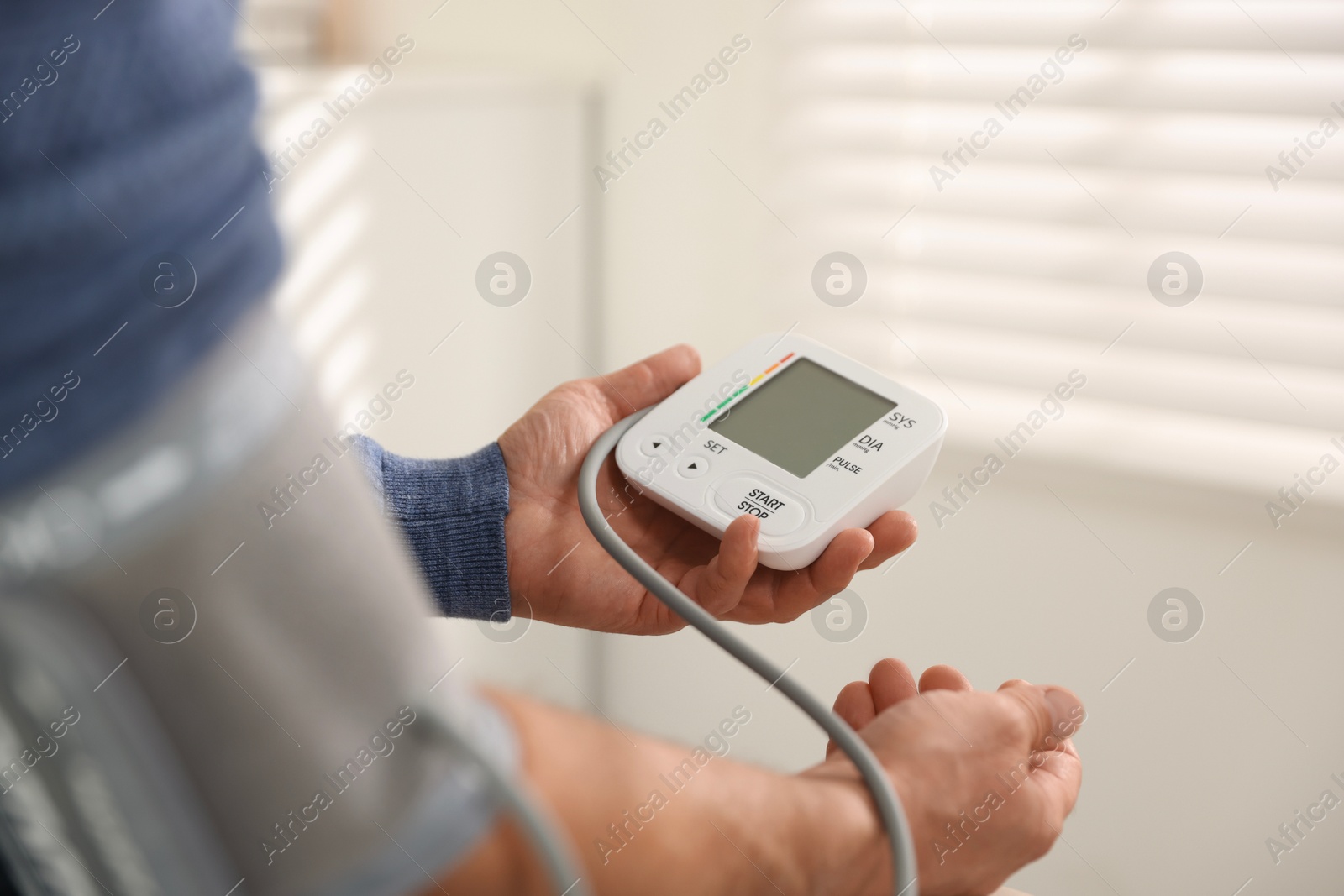 Photo of Senior man measuring blood pressure at home, closeup