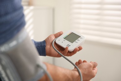 Photo of Senior man measuring blood pressure at home, closeup