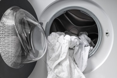 Photo of Open washing machine with clean clothes, closeup