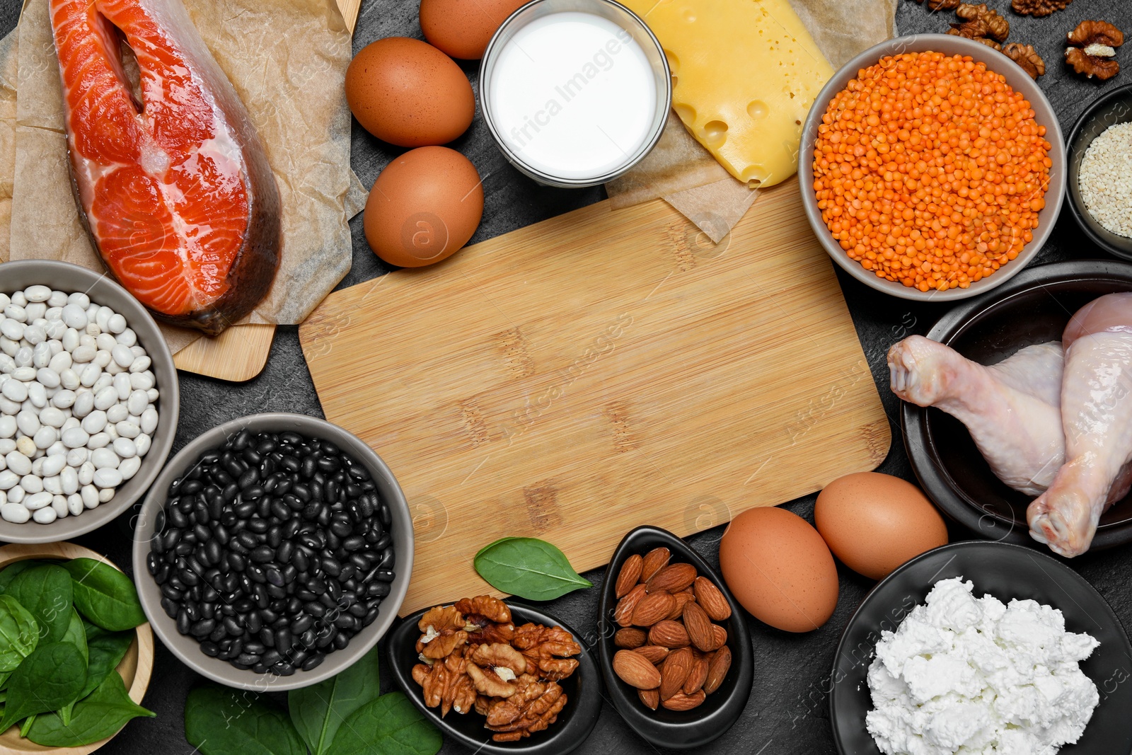 Photo of Different fresh products rich in estrogen and wooden board on grey textured table, flat lay