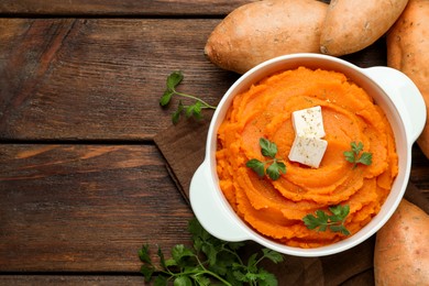Photo of Tasty mashed sweet potato with butter in bowl, fresh vegetables and parsley on wooden table, flat lay. Space for text
