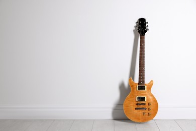 Photo of One modern electric guitar near white wall. Space for text