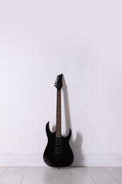 Photo of One modern electric guitar near white wall