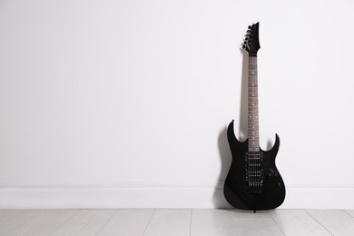 Photo of One modern electric guitar near white wall. Space for text