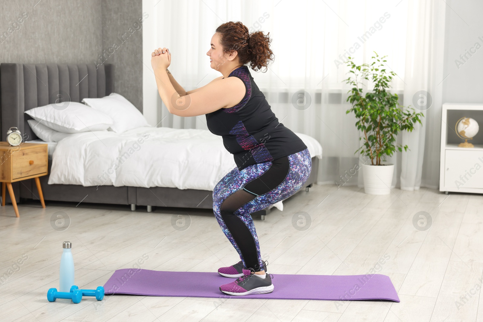 Photo of Plus size woman exercising on fitness mat at home