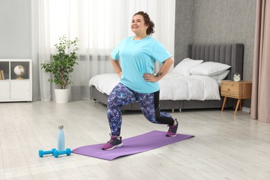 Photo of Plus size woman exercising on fitness mat at home