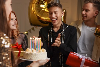 21st birthday. Group of happy friends with tasty cake having coming of age party at home