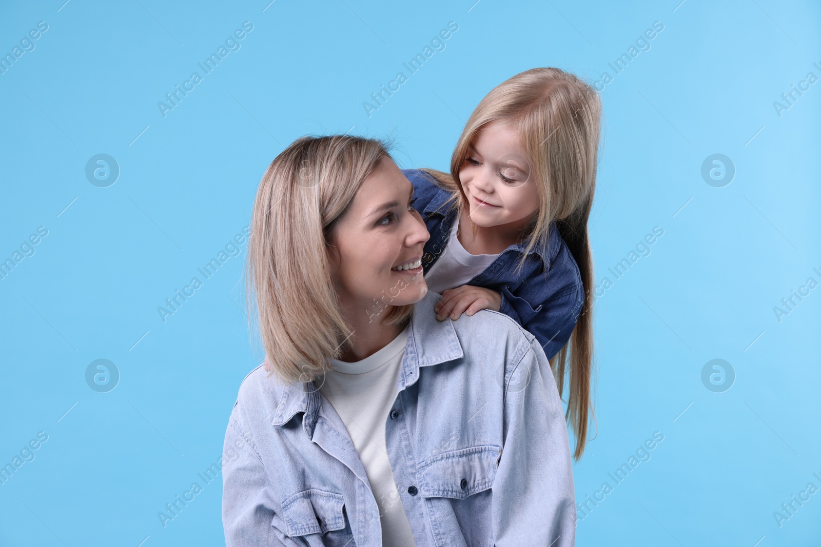 Photo of Cute little girl with her mom on light blue background. Happy Mother's Day