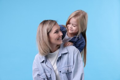 Photo of Cute little girl with her mom on light blue background. Happy Mother's Day