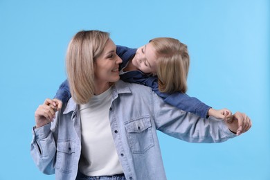 Photo of Cute little girl with her mom on light blue background. Happy Mother's Day