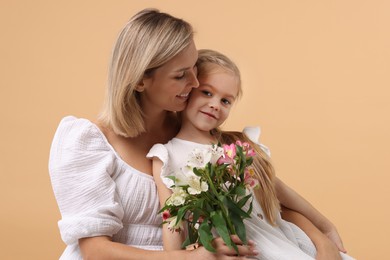 Photo of Little daughter congratulating her mom with bouquet of alstroemeria flowers on beige background. Happy Mother's Day