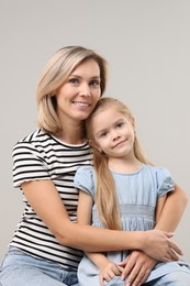 Photo of Cute little girl with her mom on gray background. Happy Mother's Day