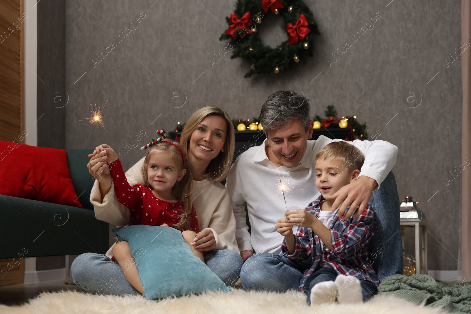 Photo of Lovely family with Christmas sparklers at home