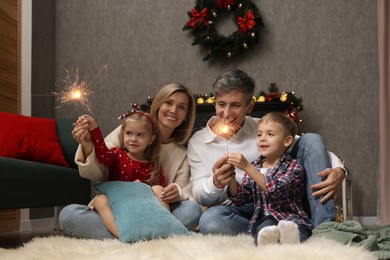 Photo of Lovely family with Christmas sparklers at home