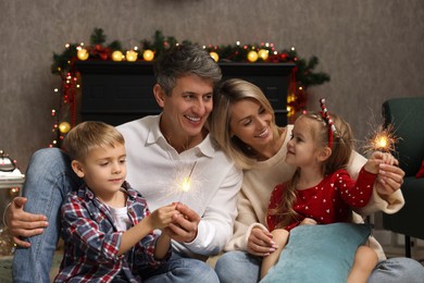 Photo of Lovely family with Christmas sparklers at home