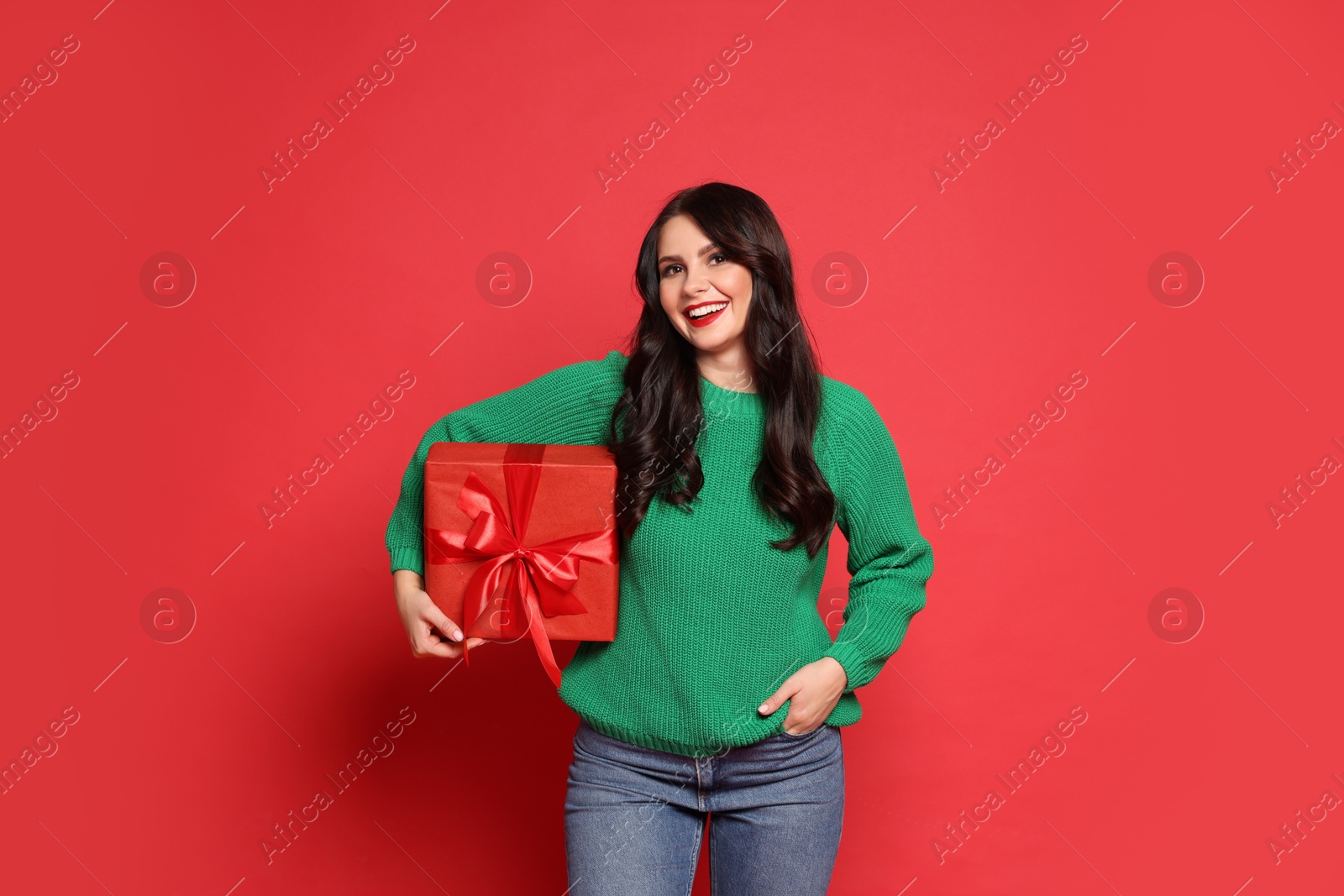 Photo of Happy woman with Christmas present on red background