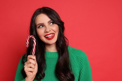 Photo of Beautiful woman with candy cane on red background, space for text. Christmas celebration