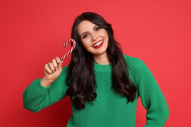 Photo of Beautiful woman with candy cane on red background. Christmas celebration