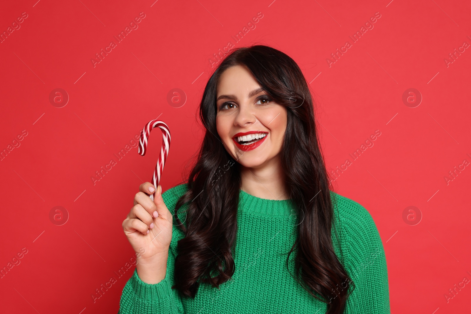 Photo of Beautiful woman with candy cane on red background. Christmas celebration