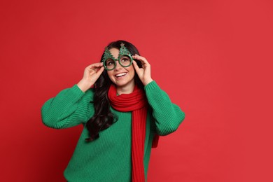 Beautiful woman with party glasses on red background, space for text. Christmas celebration