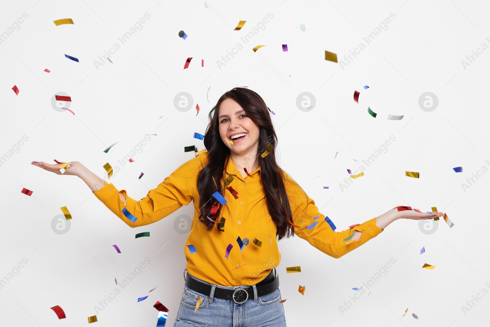 Photo of Happy woman under falling confetti on white background. Surprise party