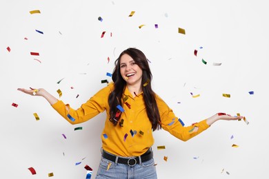 Photo of Happy woman under falling confetti on white background. Surprise party