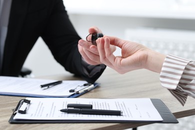 Photo of Salesman giving key to client at wooden table in office, closeup. Buying auto