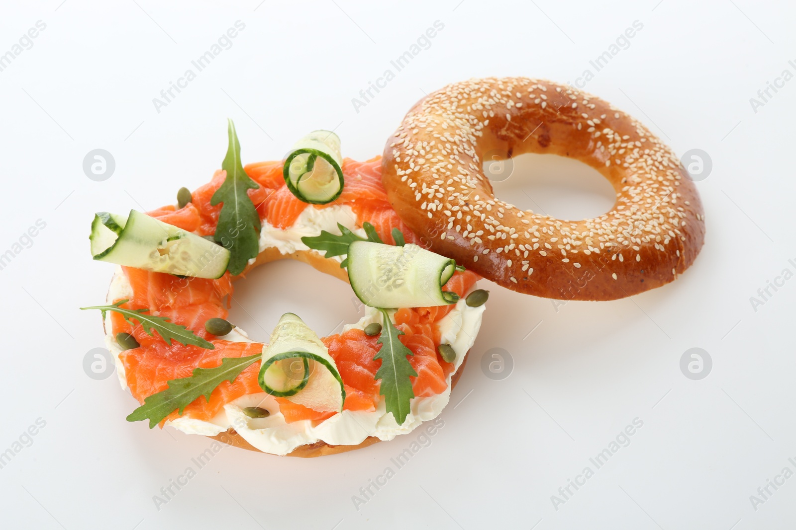 Photo of Delicious bagel with salmon, cream cheese and cucumber on white background