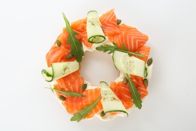 Photo of Half of delicious bagel with salmon, cream cheese and cucumber on white background, top view