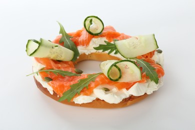 Photo of Half of delicious bagel with salmon, cream cheese and cucumber on white background, closeup