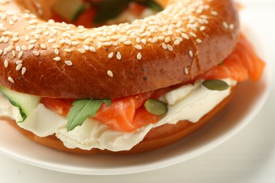 Photo of Delicious bagel with salmon and cream cheese on white table, closeup