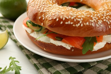 Photo of Delicious bagel with salmon, arugula and cream cheese on white wooden table, closeup