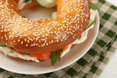 Photo of Delicious bagel with salmon, arugula and cream cheese on white table, closeup