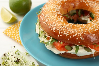 Photo of Delicious bagel with salmon, microgreens, arugula and cream cheese on white table, closeup