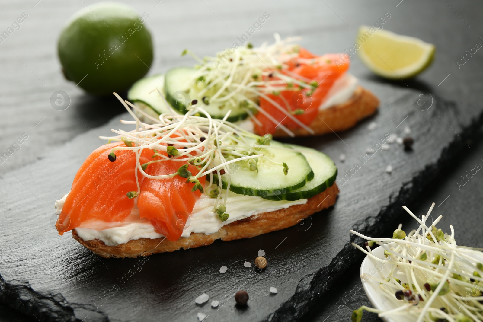 Photo of Delicious bruschette with salmon, cream cheese and cucumber on grey table, closeup